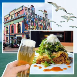 a hand holding a glass of beer and a plate of food. Best pubs in Brighton